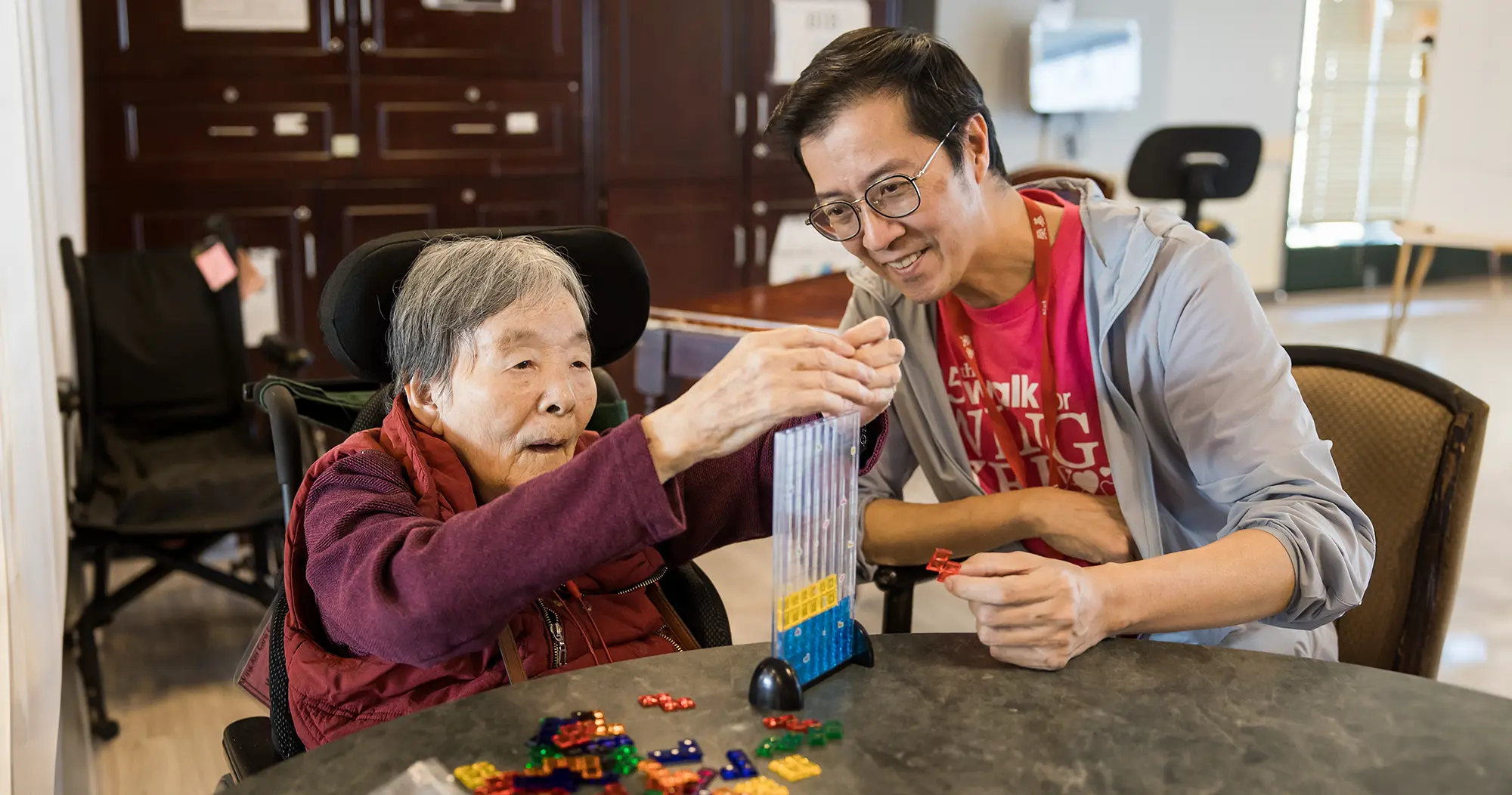Wing Kei reesident and staff member interacting over a game