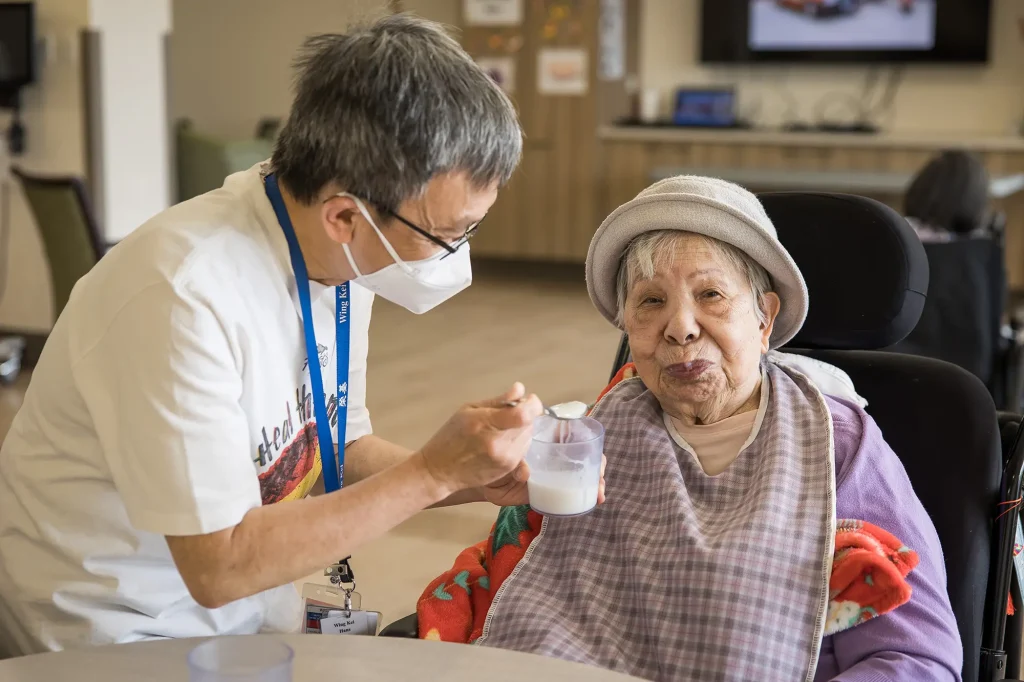 Wing Kei volunteer helping feed resident
